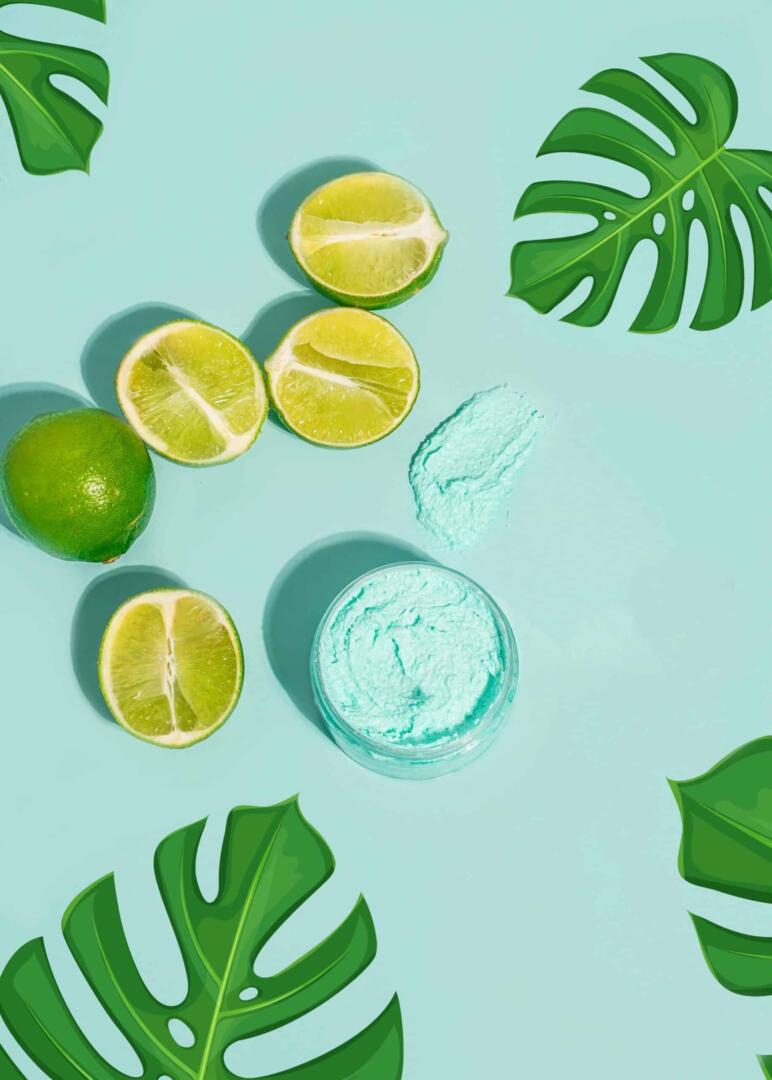 Green limes and a bowl of green scrub on a light blue background with green leaves.